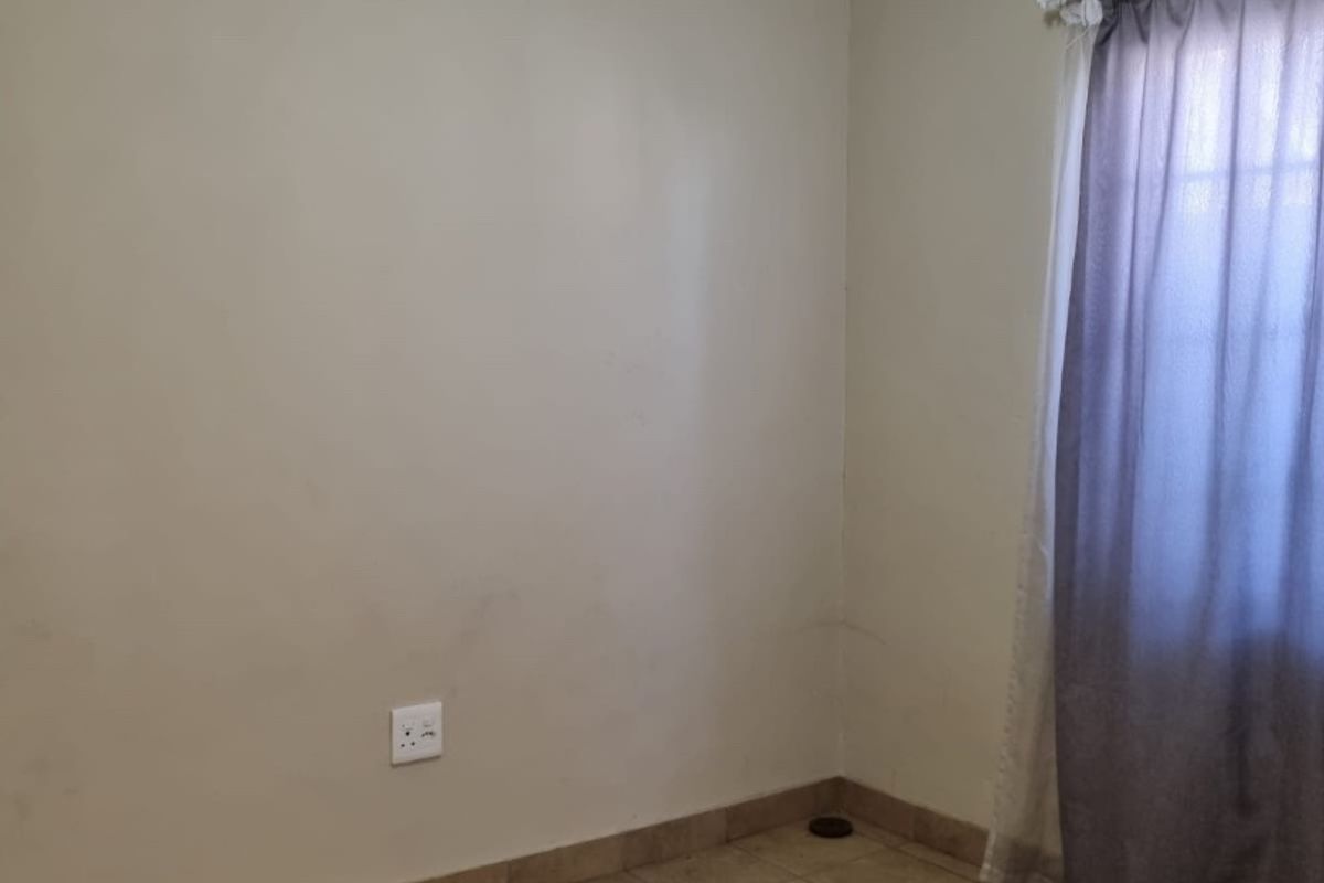 An empty bedroom featuring tiled flooring, neutral walls, and coving, providing a blank canvas for personalization.