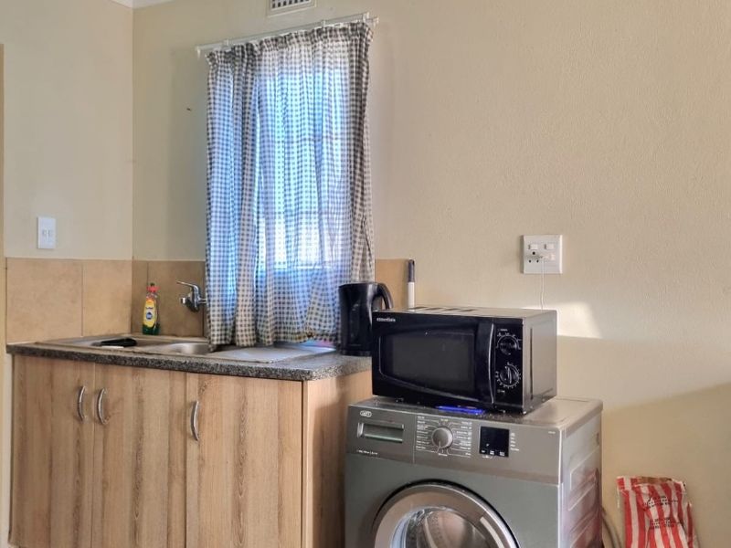 A functional laundry area featuring built-in cabinetry, a sink, and tiled flooring, providing essential utility space for the home.