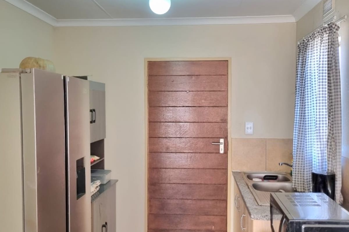 A functional kitchen featuring built-in cabinetry, a double sink with granite countertops, and tiled flooring, providing a practical workspace.