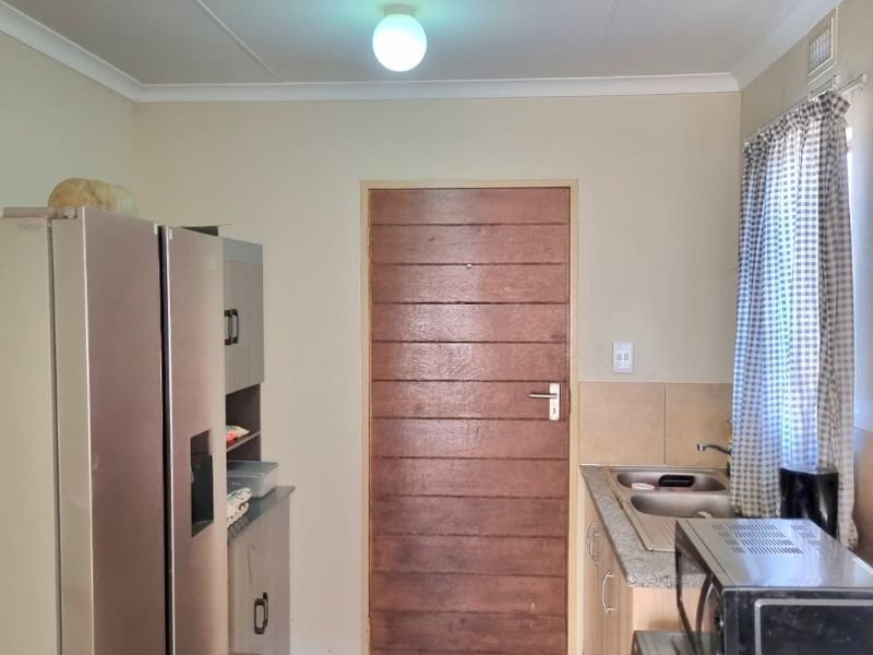 A functional kitchen featuring built-in cabinetry, a double sink with granite countertops, and tiled flooring, providing a practical workspace.