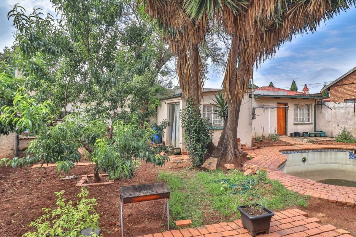 Rear garden area featuring a swimming pool, brick paving, and mature trees, with direct access to the house via a sliding door.
