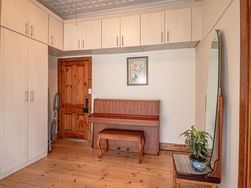 Bedroom featuring extensive built-in cabinetry, original timber flooring, and a decorative pressed metal ceiling, offering ample storage and classic character.