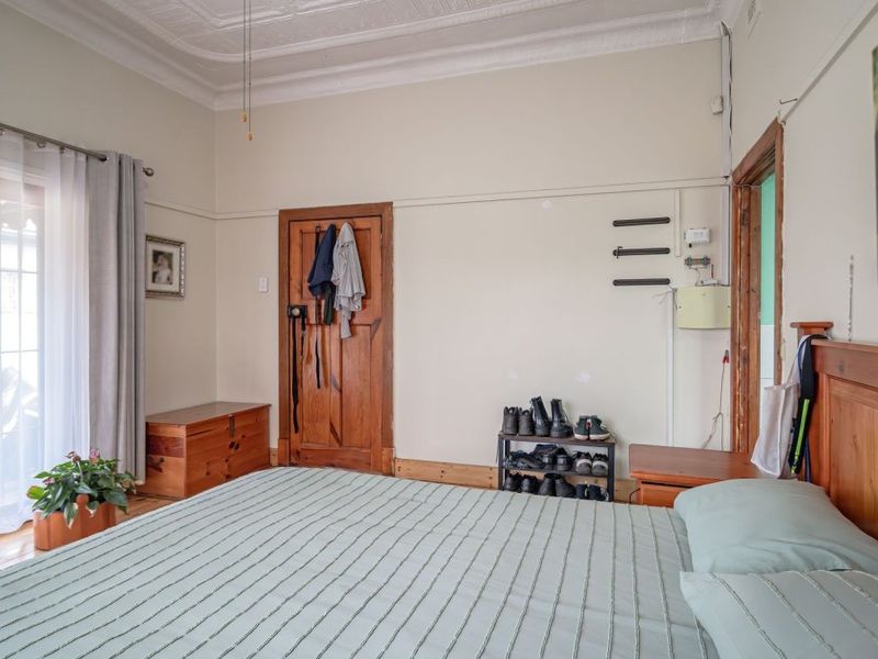 A bedroom featuring timber flooring, decorative ceiling details, and a sliding glass door providing access to the exterior.