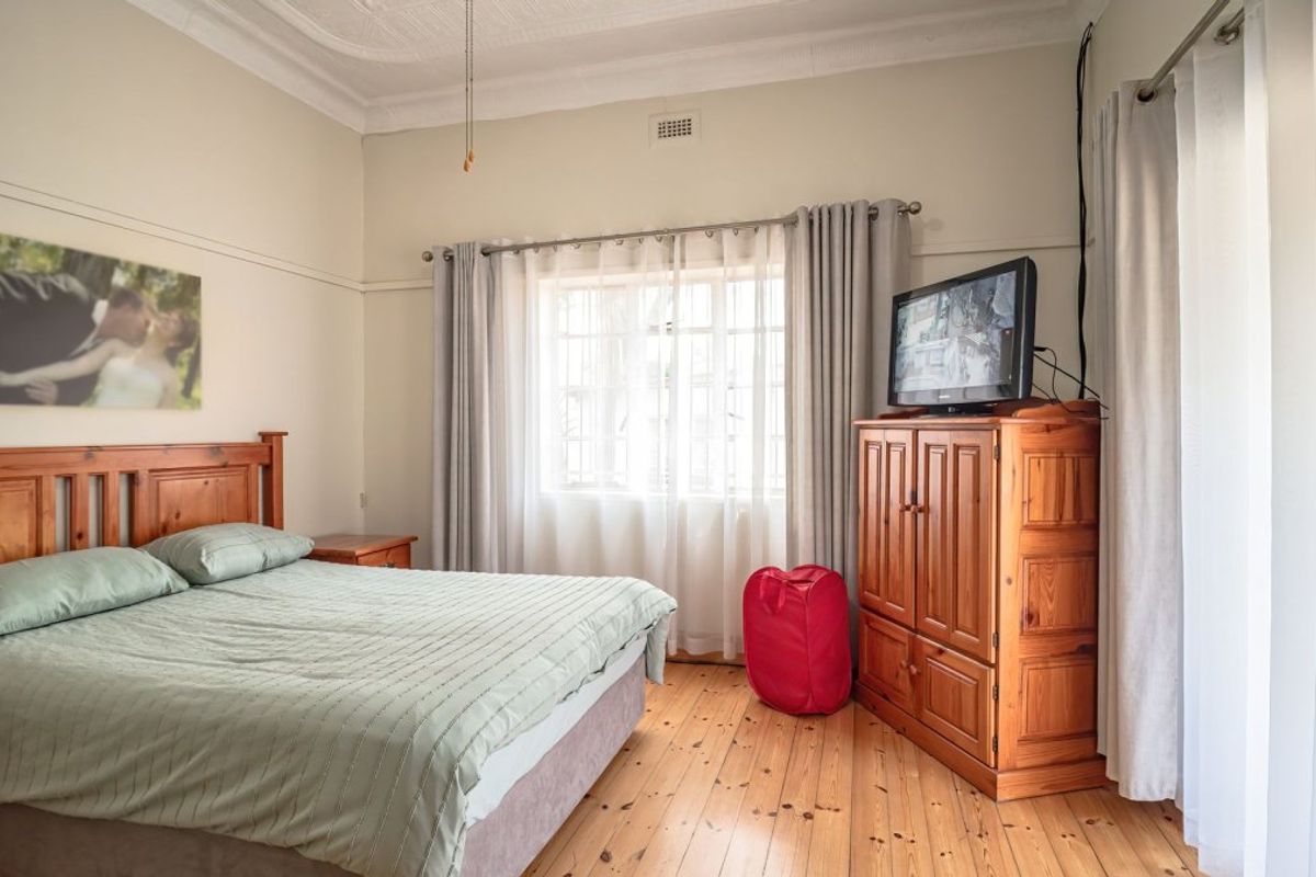 A well-lit bedroom featuring original timber flooring, ornate ceiling cornicing, and classic picture rails, offering a comfortable and character-filled living space.