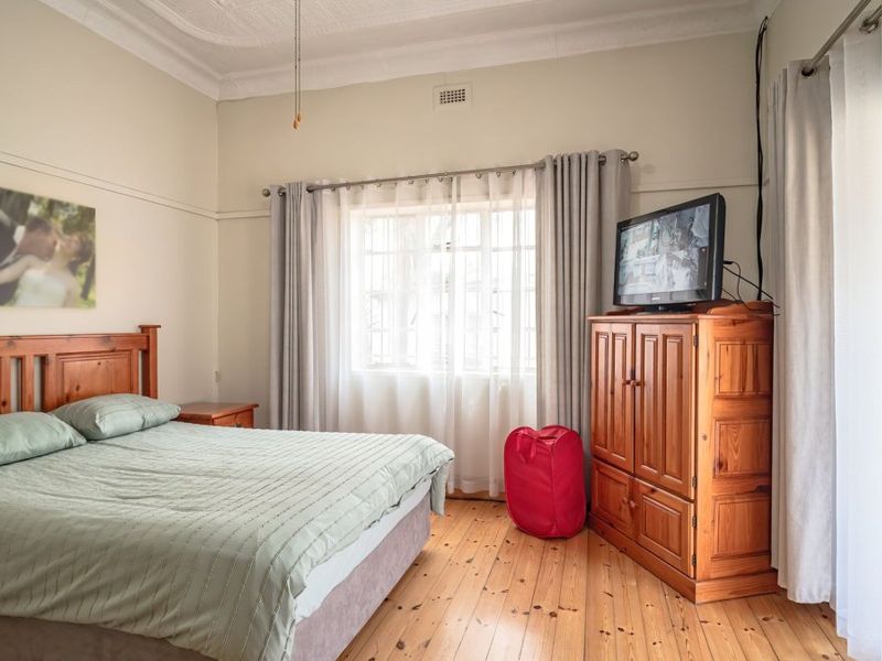 A well-lit bedroom featuring original timber flooring, ornate ceiling cornicing, and classic picture rails, offering a comfortable and character-filled living space.