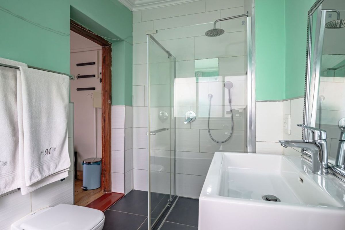 A functional bathroom featuring a walk-in shower with glass screen, modern basin, and tiled finishes. The space is well-lit and clean.