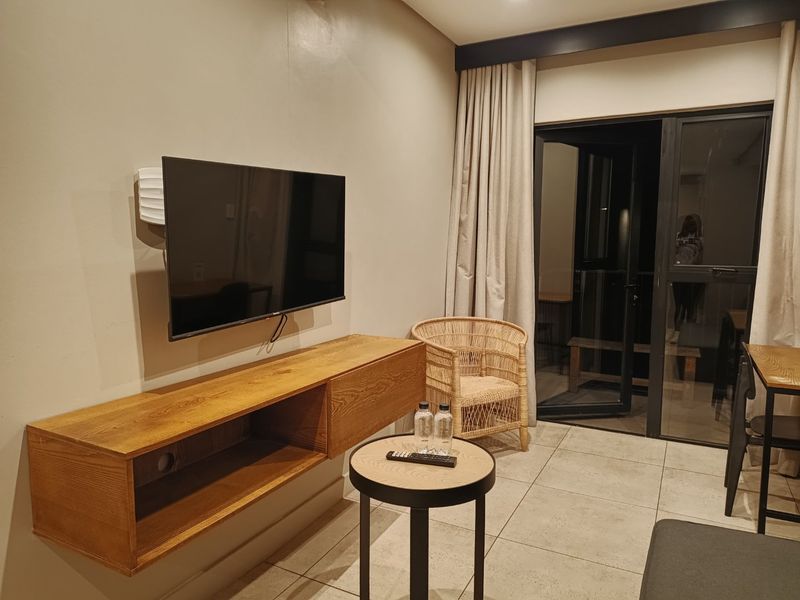 A modern living area featuring tiled flooring, recessed lighting, and a sliding glass door providing access to an outdoor space.