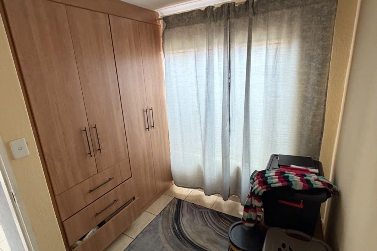 A bedroom featuring built-in wooden cupboards and tiled flooring, providing functional storage space.