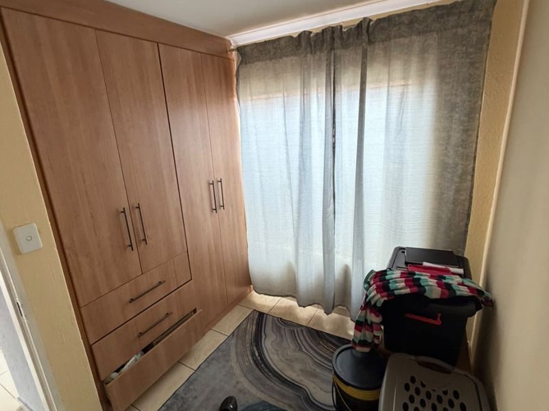 A bedroom featuring built-in wooden cupboards and tiled flooring, providing functional storage space.