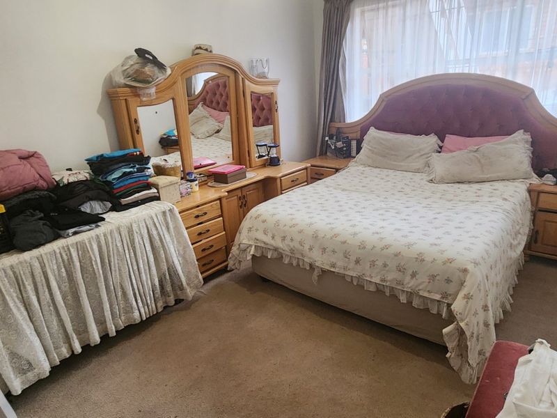 A standard bedroom featuring carpeted flooring and large windows with curtain tracks, providing a functional space for rest.