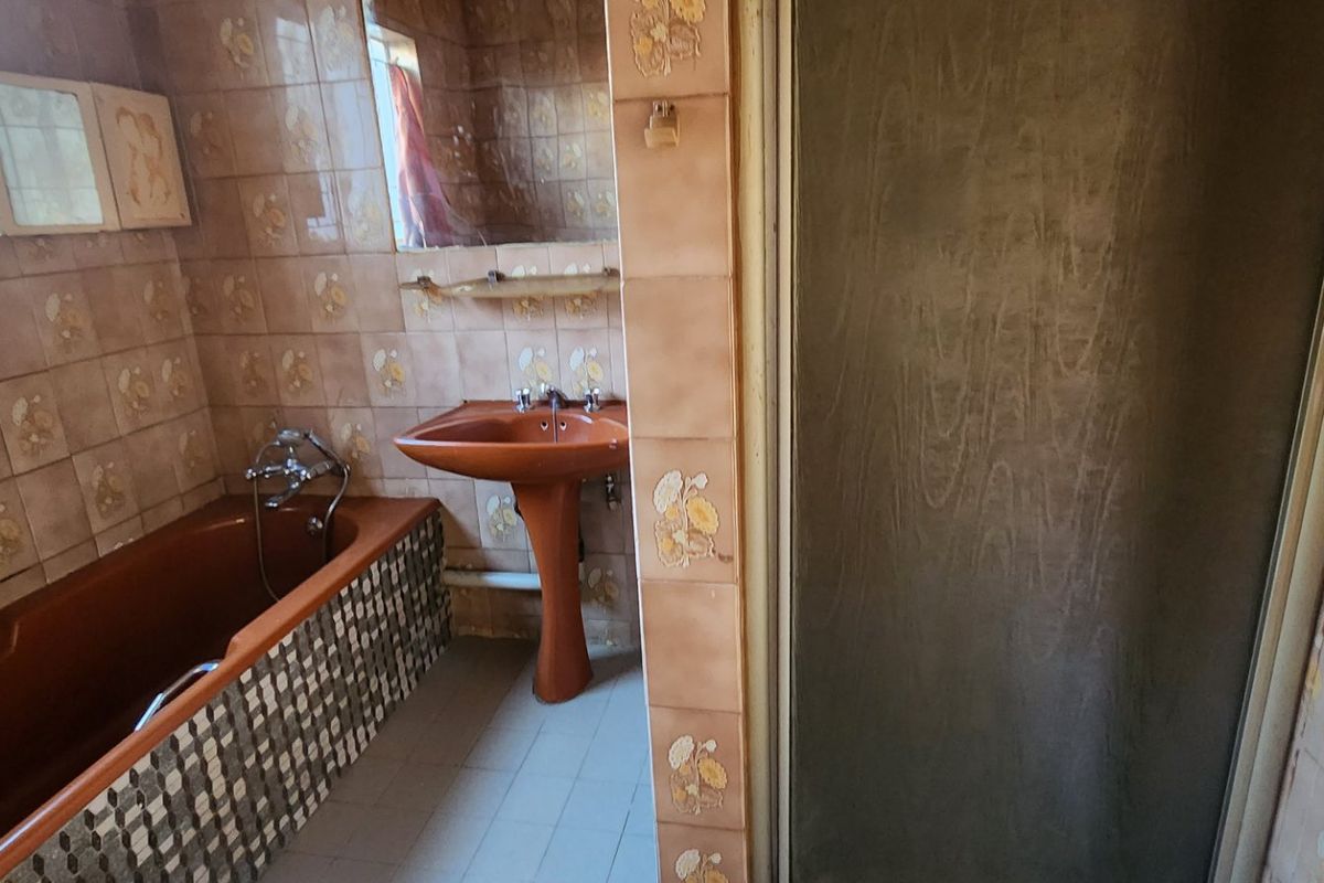A dated bathroom featuring a pedestal basin, built-in bathtub, and separate shower enclosure with original wall tiling.