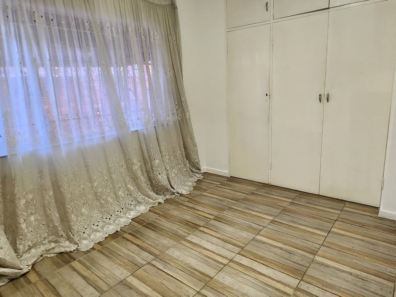 A vacant bedroom featuring tiled flooring and built-in cupboards, offering a clean and neutral space ready for personalization.
