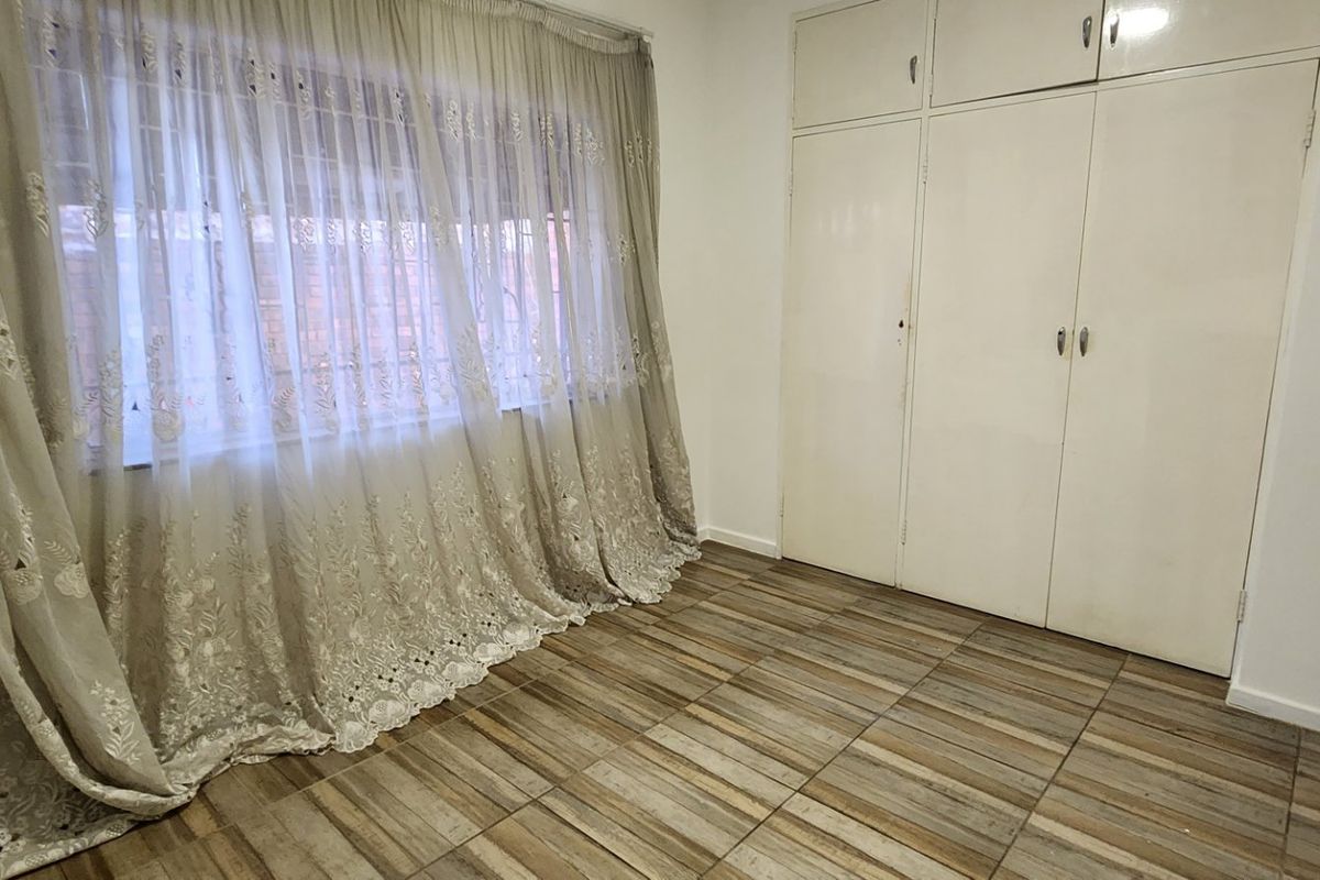 An empty bedroom featuring tiled flooring and built-in cupboards with overhead storage compartments.