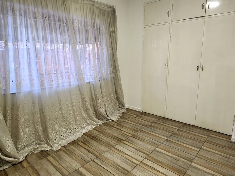 An empty bedroom featuring tiled flooring and built-in cupboards with overhead storage compartments.