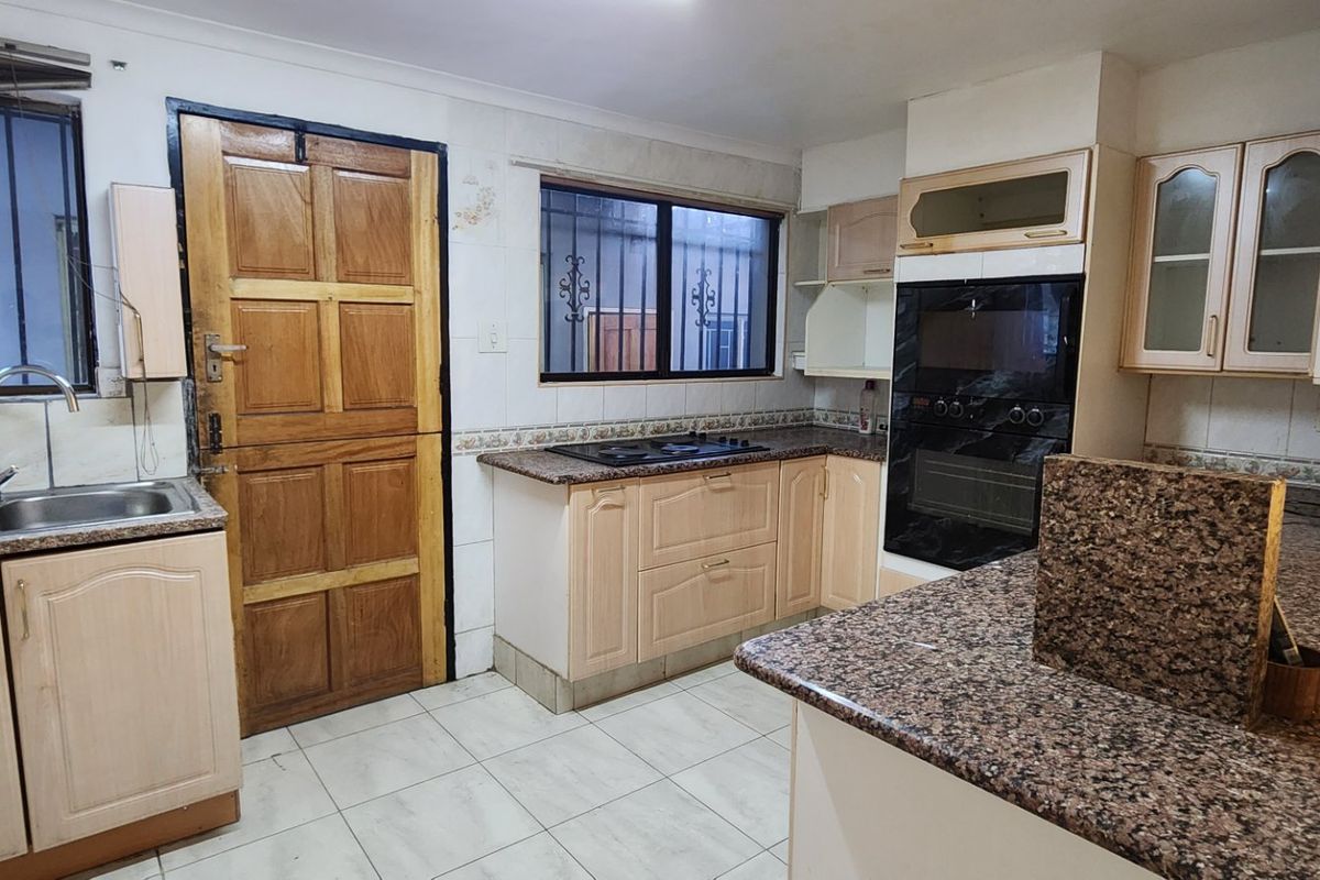 A functional kitchen featuring granite countertops, built-in oven, hob, and ample cabinetry, offering a solid foundation for a modern cosmetic update.