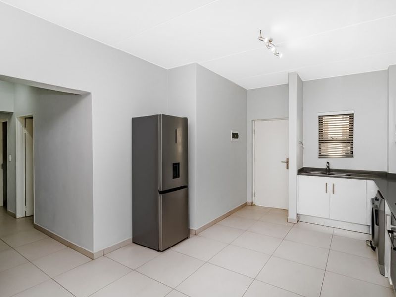 A clean and functional kitchen featuring tiled flooring, built-in cabinetry, a double sink, and neutral wall finishes.