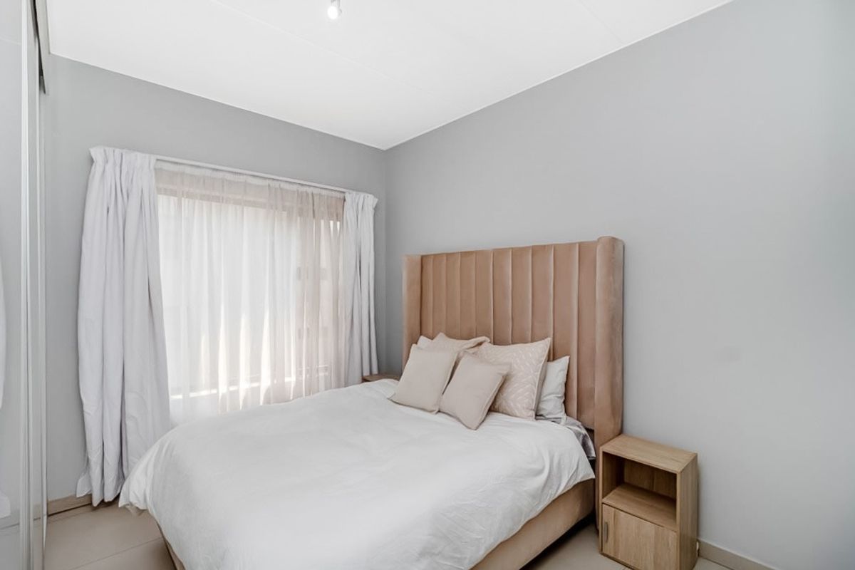 A well-maintained bedroom featuring neutral wall tones, tiled flooring, and a built-in wardrobe, offering a clean and comfortable living space.