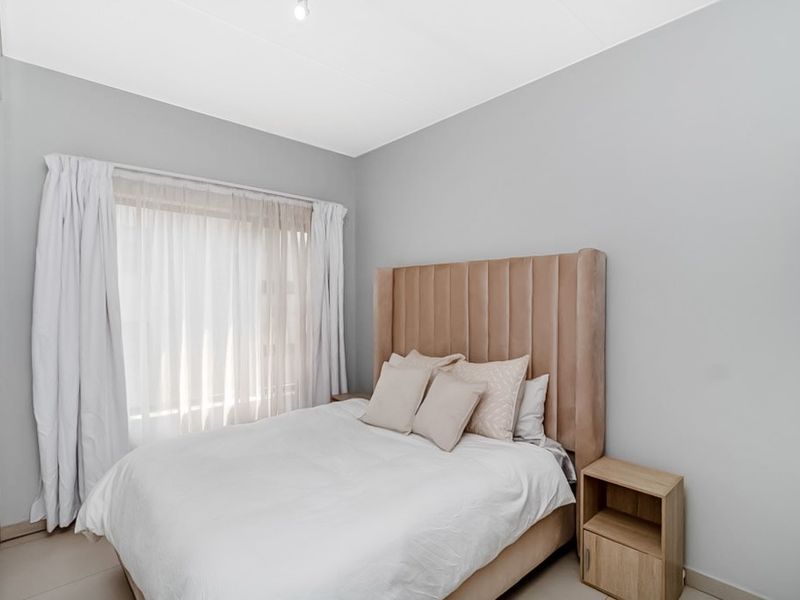 A well-maintained bedroom featuring neutral wall tones, tiled flooring, and a built-in wardrobe, offering a clean and comfortable living space.