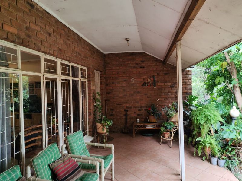 A covered patio area featuring exposed brick walls, tiled flooring, and large glass sliding doors providing access to the interior living space.