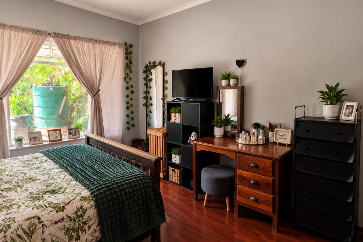 A well-maintained bedroom featuring warm-toned laminate flooring and a large window that provides ample natural light.