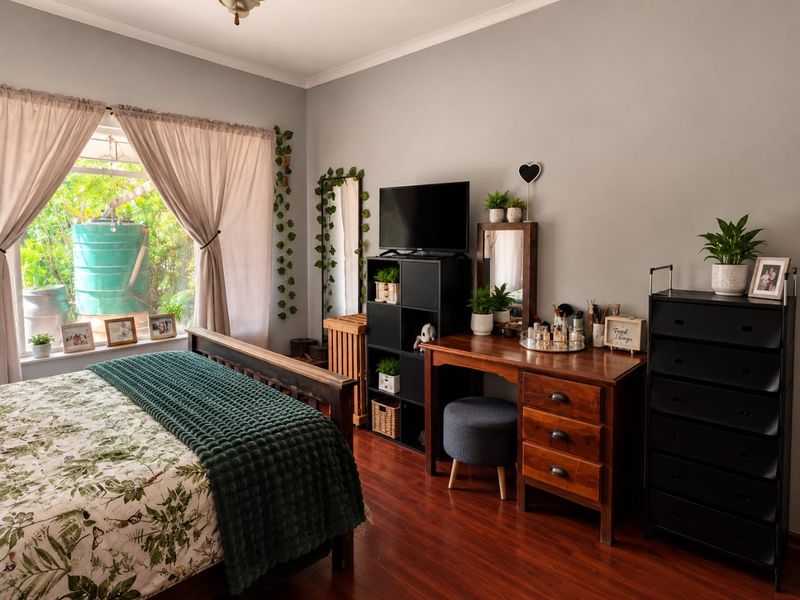 A well-maintained bedroom featuring warm-toned laminate flooring and a large window that provides ample natural light.