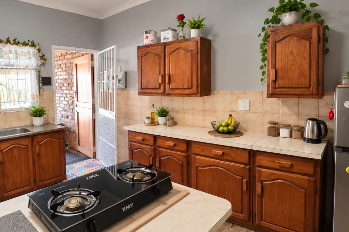 A functional kitchen featuring warm-toned wooden cabinetry, laminate countertops, a gas cooktop, and a double basin sink with a tiled backsplash.