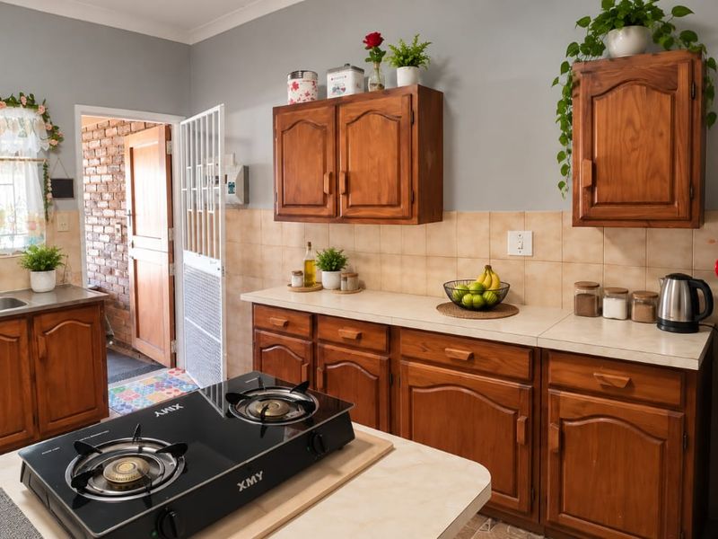 A functional kitchen featuring warm-toned wooden cabinetry, laminate countertops, a gas cooktop, and a double basin sink with a tiled backsplash.