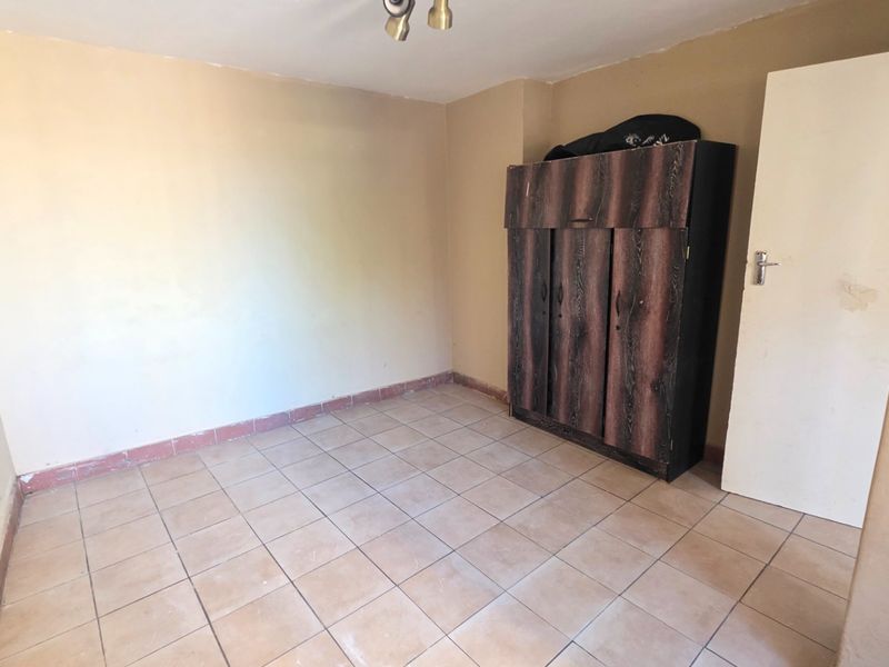A simple bedroom featuring tiled flooring and neutral wall finishes, offering a blank canvas for potential updates or interior design improvements.