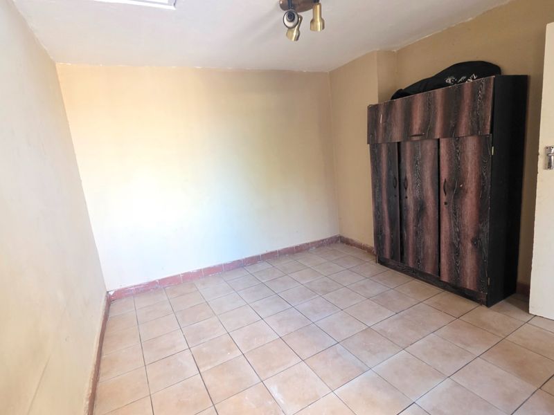 A vacant bedroom featuring tiled flooring and neutral wall tones, offering a blank canvas for personalization.