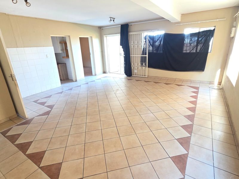 Spacious open-plan living area featuring tiled flooring, a security gate, and direct access to an outdoor space.