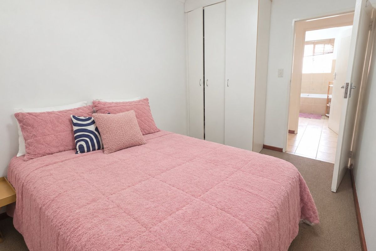 A bedroom featuring built-in wardrobes, carpet flooring, and direct access to an adjoining bathroom.