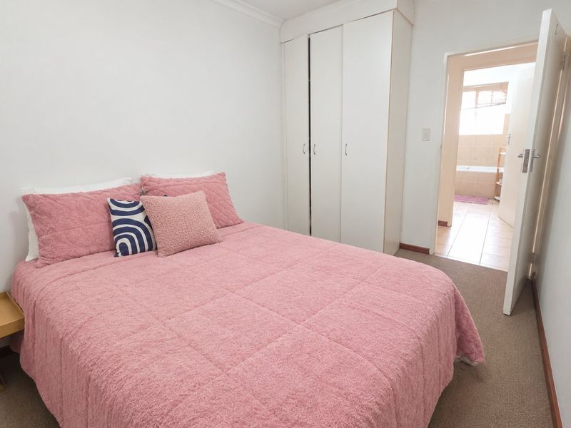 A bedroom featuring built-in wardrobes, carpet flooring, and direct access to an adjoining bathroom.