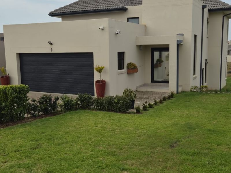 A modern double-story residential home featuring a tiled roof, integrated double garage, paved driveway, and well-maintained front lawn.