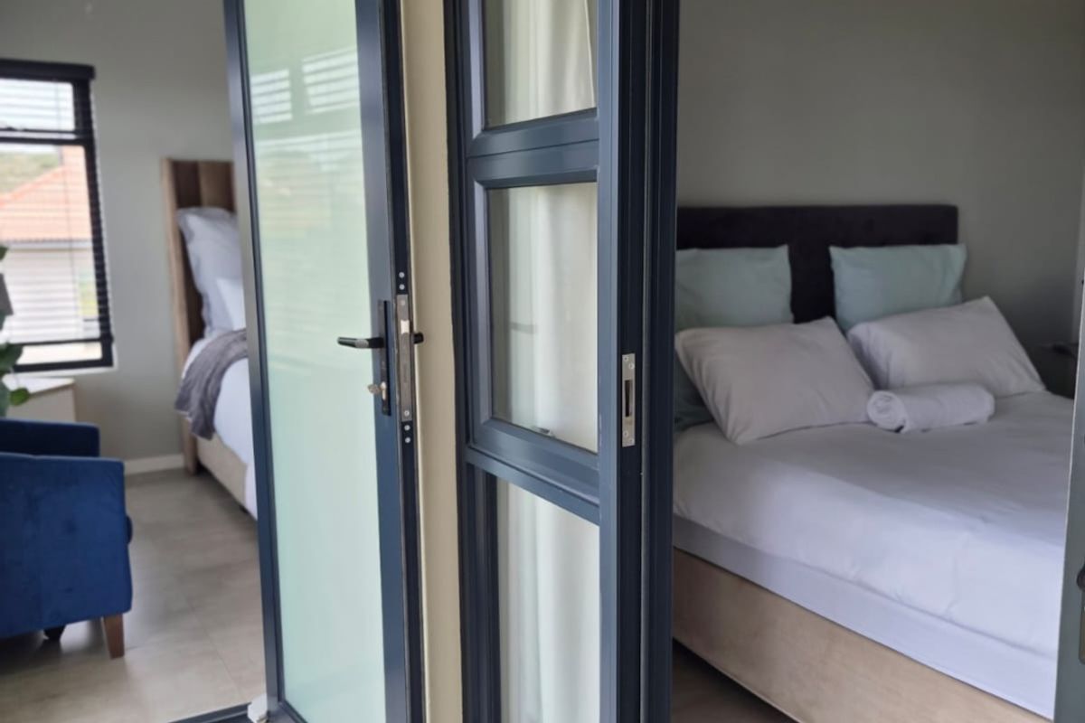 A view into a bedroom featuring modern aluminium framed glass doors and neutral tiled flooring, providing a clean and contemporary aesthetic.