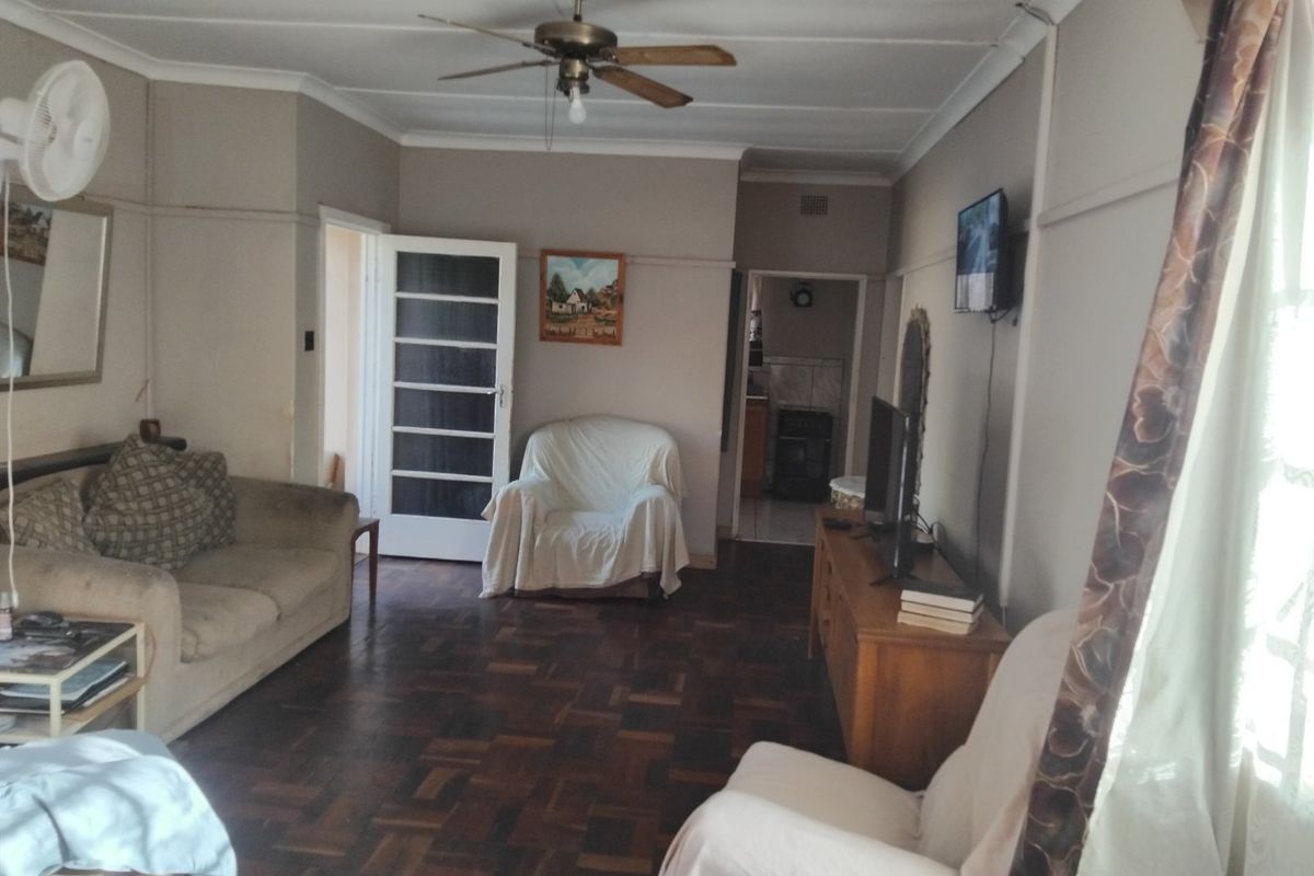 A living room featuring traditional parquet flooring, a ceiling fan, and classic picture rails, offering a comfortable and functional living space.