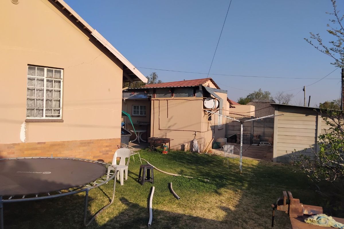 Rear view of the property showing the main house structure, a secondary outbuilding, and a garden area with paved sections.