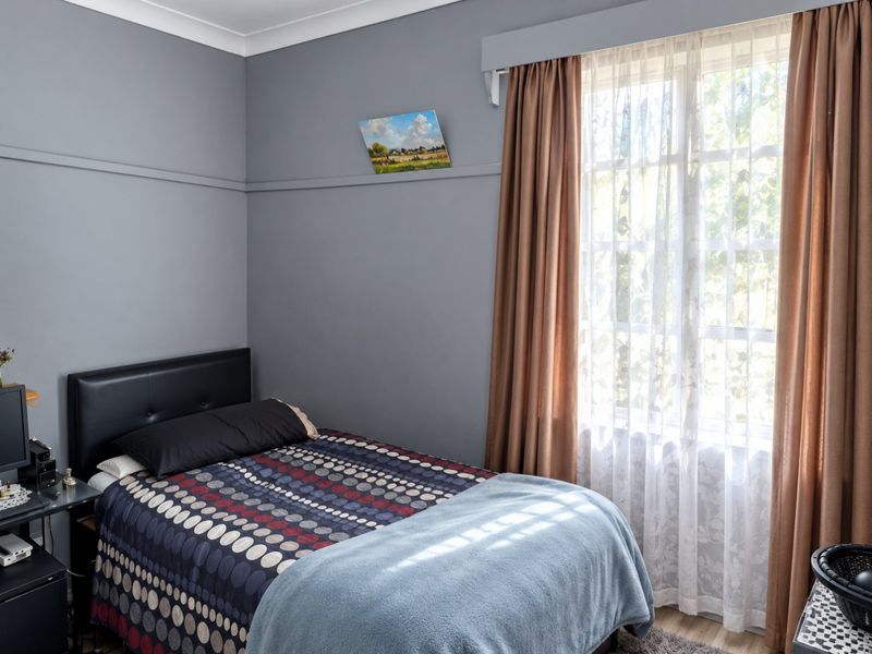 A bedroom featuring grey walls, a picture rail, coving, and a window with curtains.