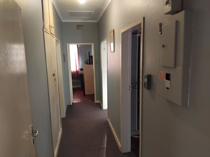 A functional hallway featuring built-in storage cupboards, an electrical distribution board, and a security alarm keypad, providing access to multiple rooms.