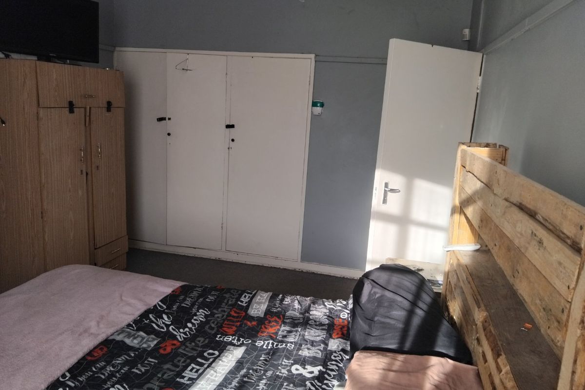 A bedroom featuring built-in cupboards and a standard internal door, requiring cosmetic updates to the walls and ceiling to improve the overall finish.