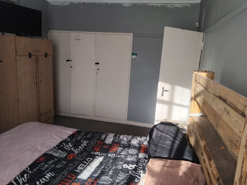 A bedroom featuring built-in cupboards and a standard internal door, requiring cosmetic updates to the walls and ceiling to improve the overall finish.