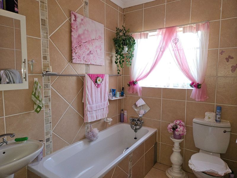 A functional bathroom featuring tiled walls and flooring, equipped with a bathtub, pedestal basin, and toilet.