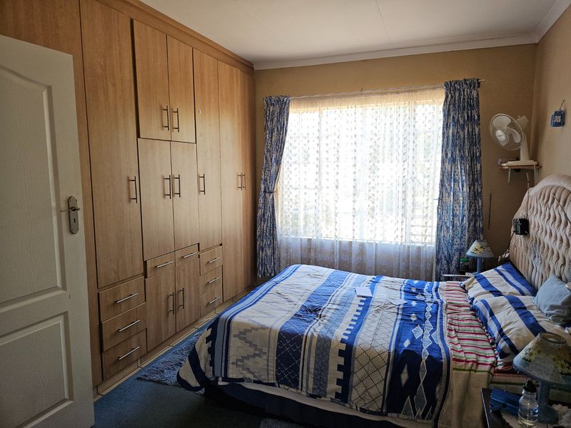 A bedroom featuring extensive built-in wooden cabinetry and a large window providing natural light.