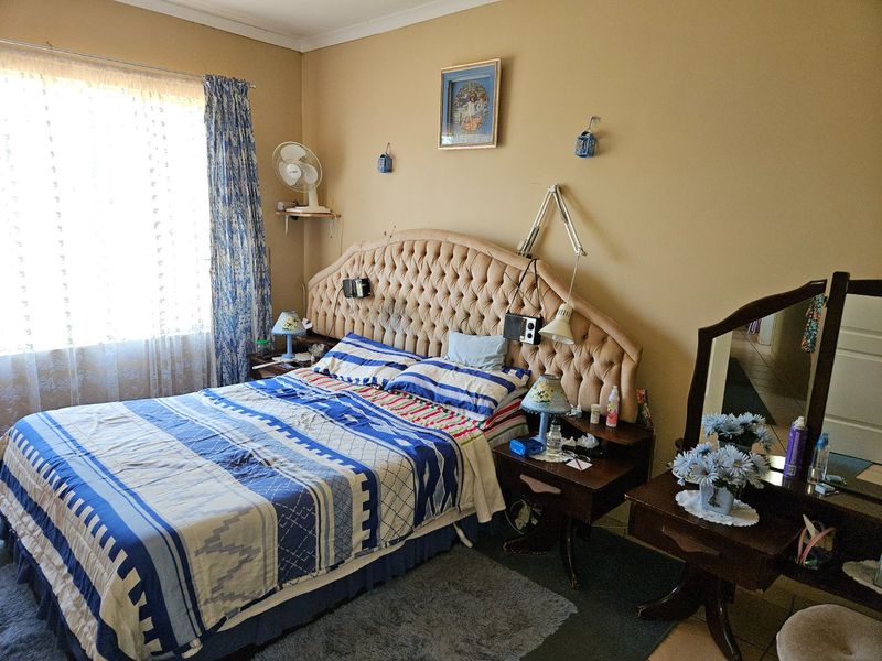A standard bedroom featuring neutral wall paint, coving, and a large window with curtain rails, providing a functional space for rest.