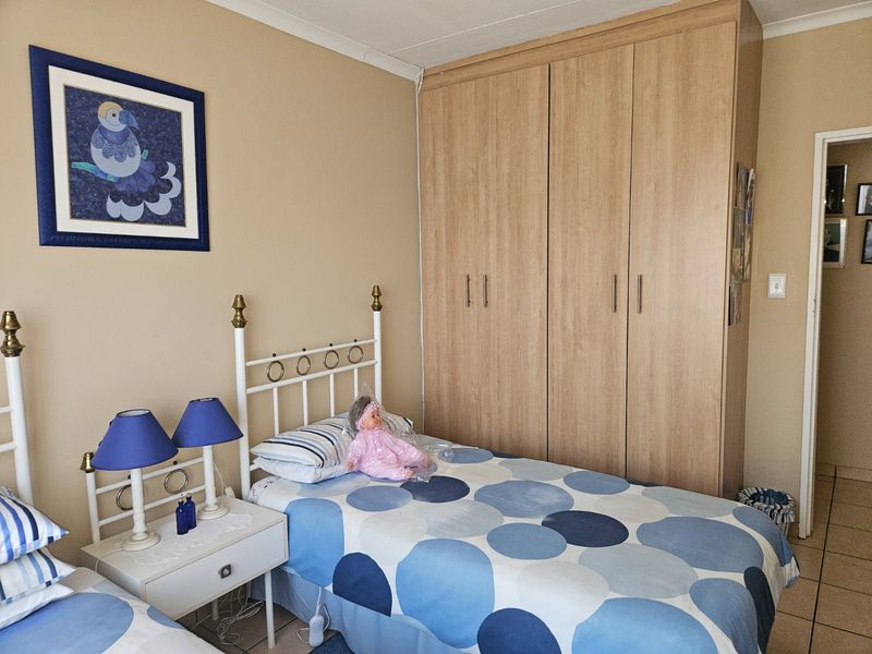 A functional bedroom featuring a large built-in wooden wardrobe, tiled flooring, and neutral wall finishes.