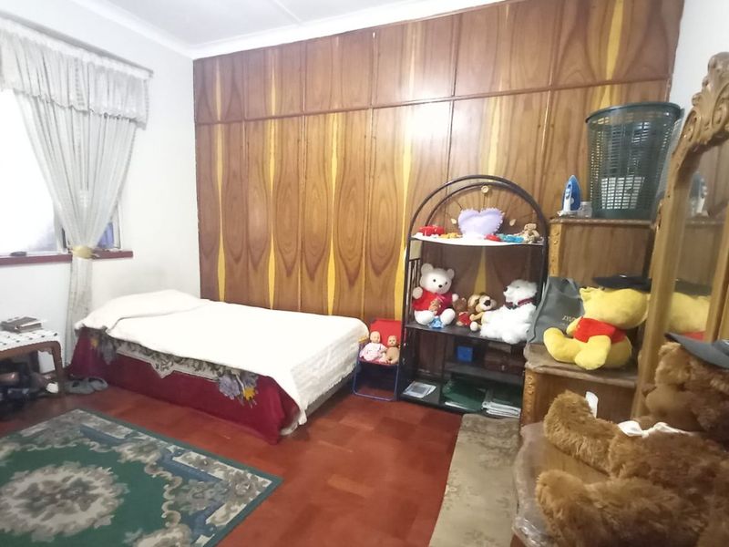 A bedroom featuring parquet flooring and extensive floor-to-ceiling built-in wooden cabinetry, offering ample storage space.