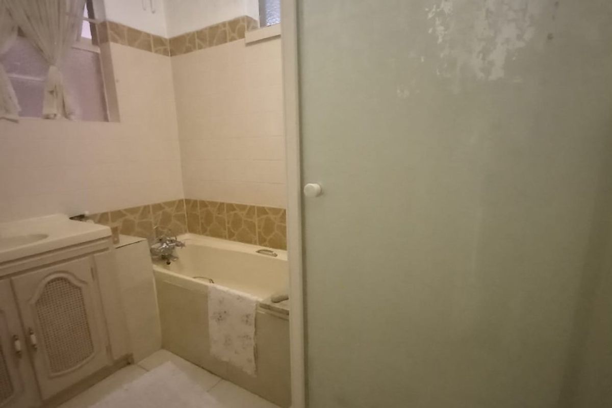 A dated bathroom featuring a built-in vanity, bathtub, and separate shower enclosure with tiled finishes, requiring cosmetic updates to modernize the space.