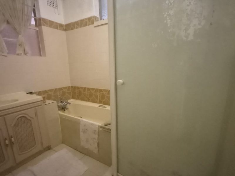 A dated bathroom featuring a built-in vanity, bathtub, and separate shower enclosure with tiled finishes, requiring cosmetic updates to modernize the space.