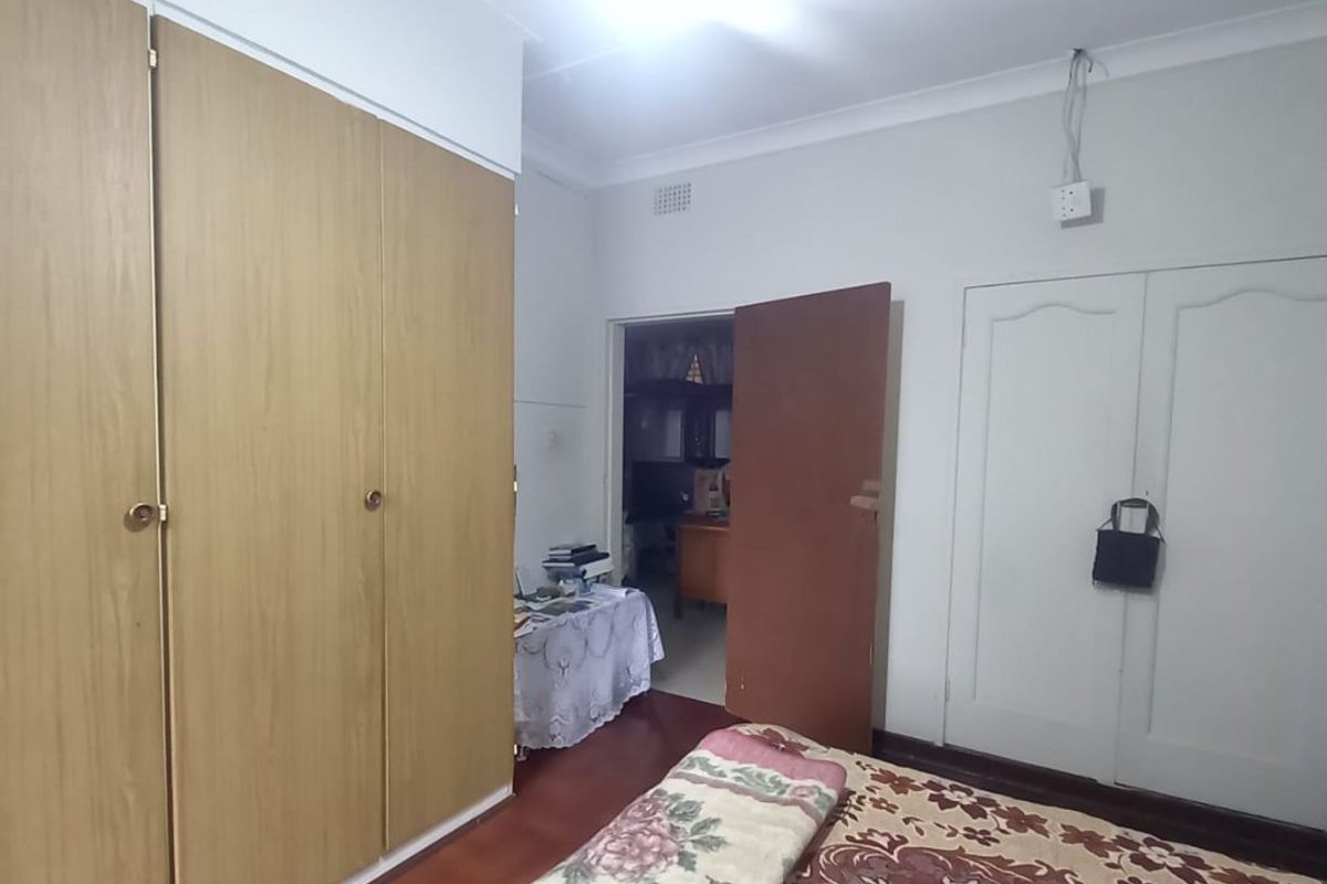 A bedroom featuring wooden flooring, built-in cupboards, and coved ceilings. The space requires minor cosmetic updates and electrical finishing.