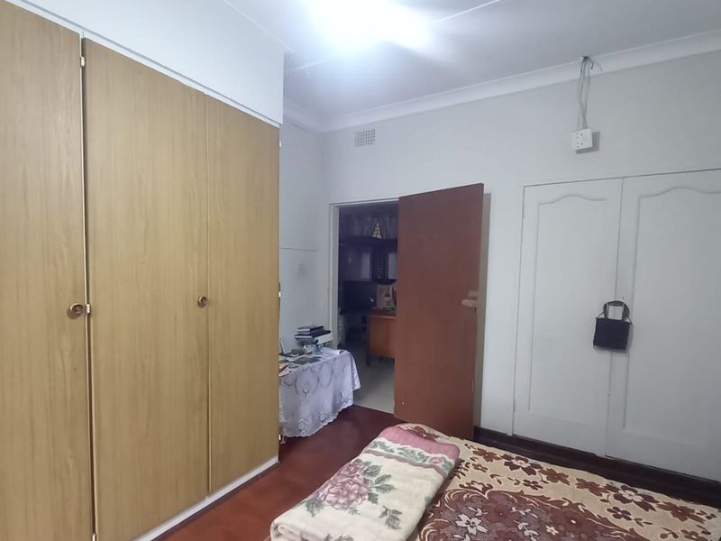 A bedroom featuring wooden flooring, built-in cupboards, and coved ceilings. The space requires minor cosmetic updates and electrical finishing.