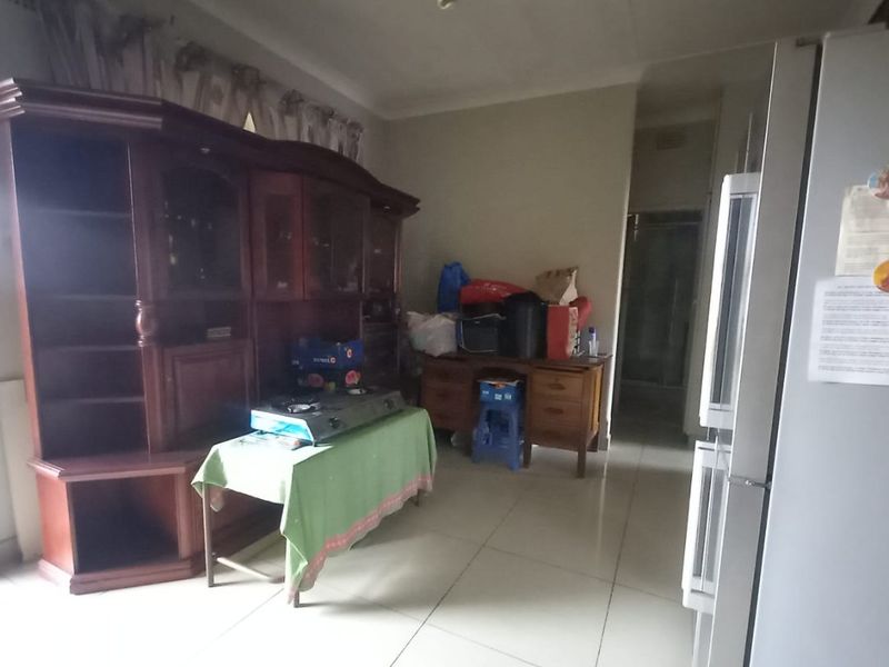 A living area featuring tiled flooring and coved ceiling details, offering a functional space that could benefit from modern updates and improved lighting.